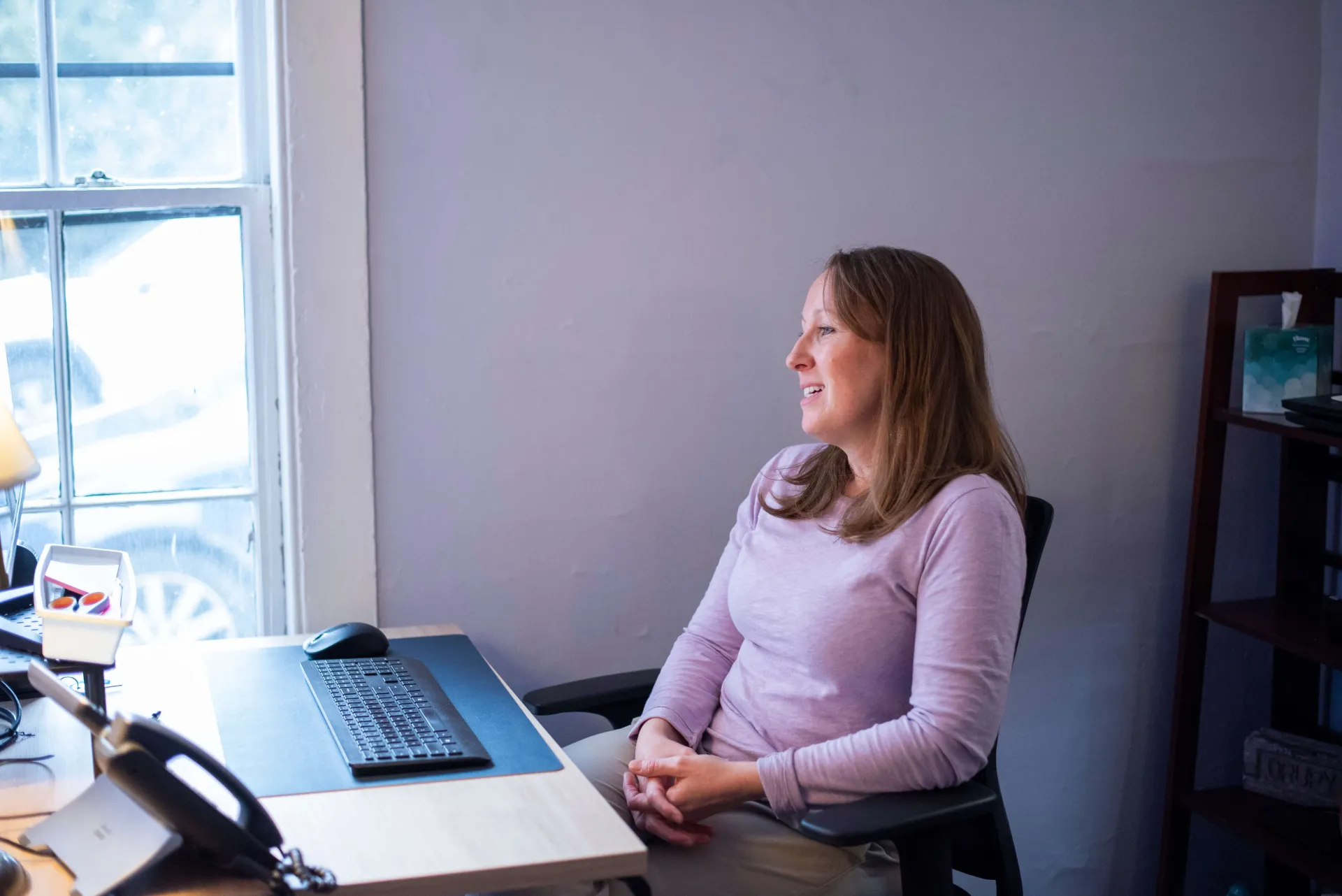 a white female counselor conducts a telehealth appointment in a sunlit room