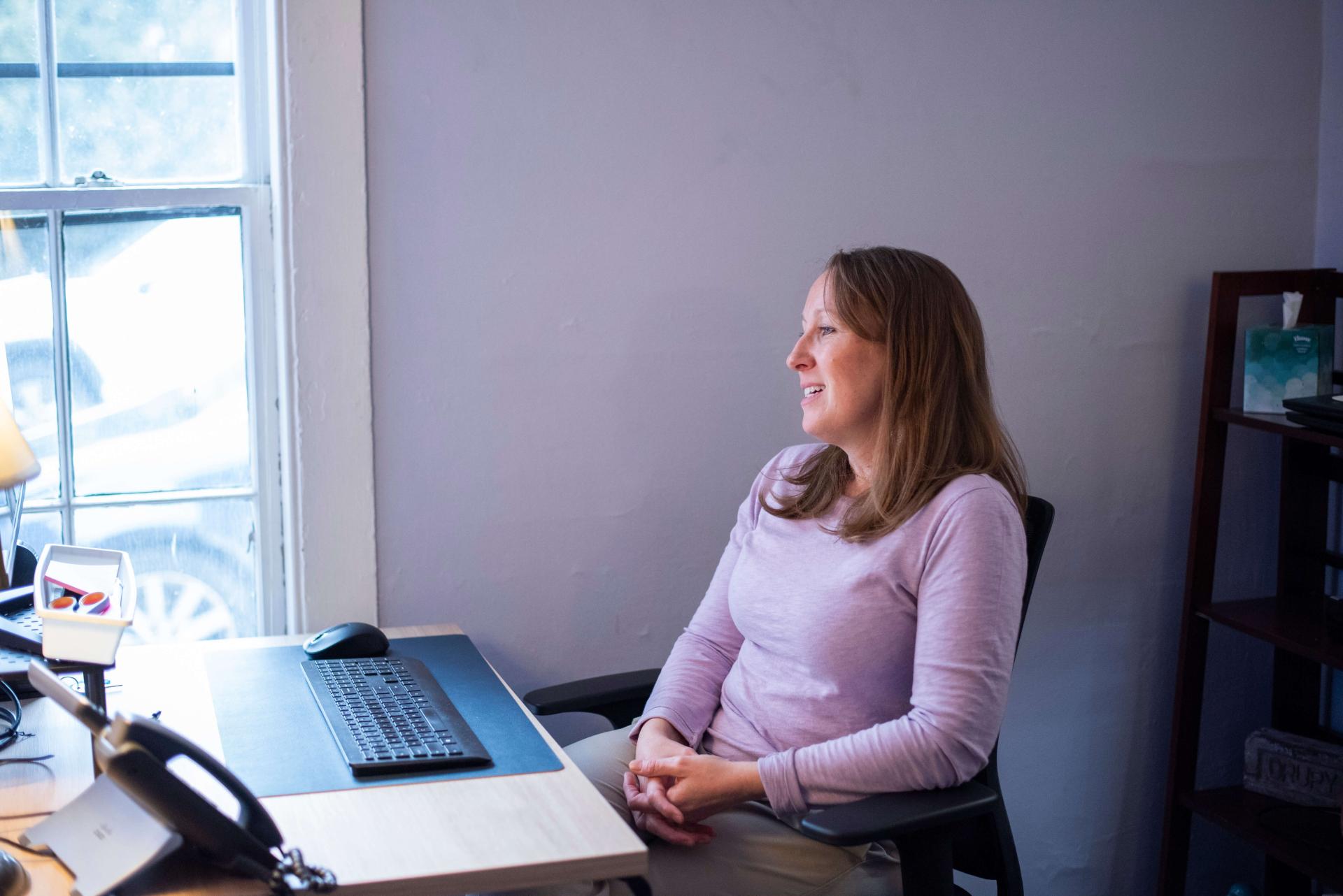 a white female counselor conducts a telehealth appointment in a sunlit room
