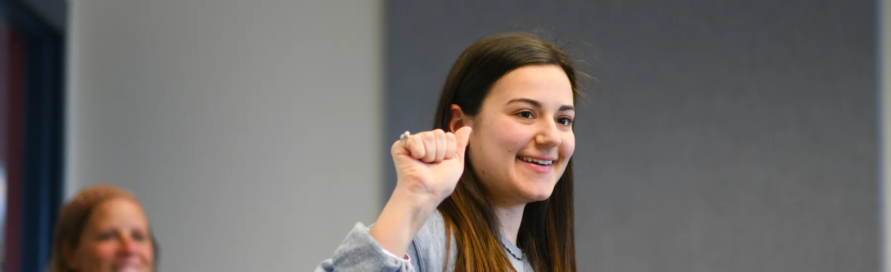 ASL student smiling as she works on signing in class.