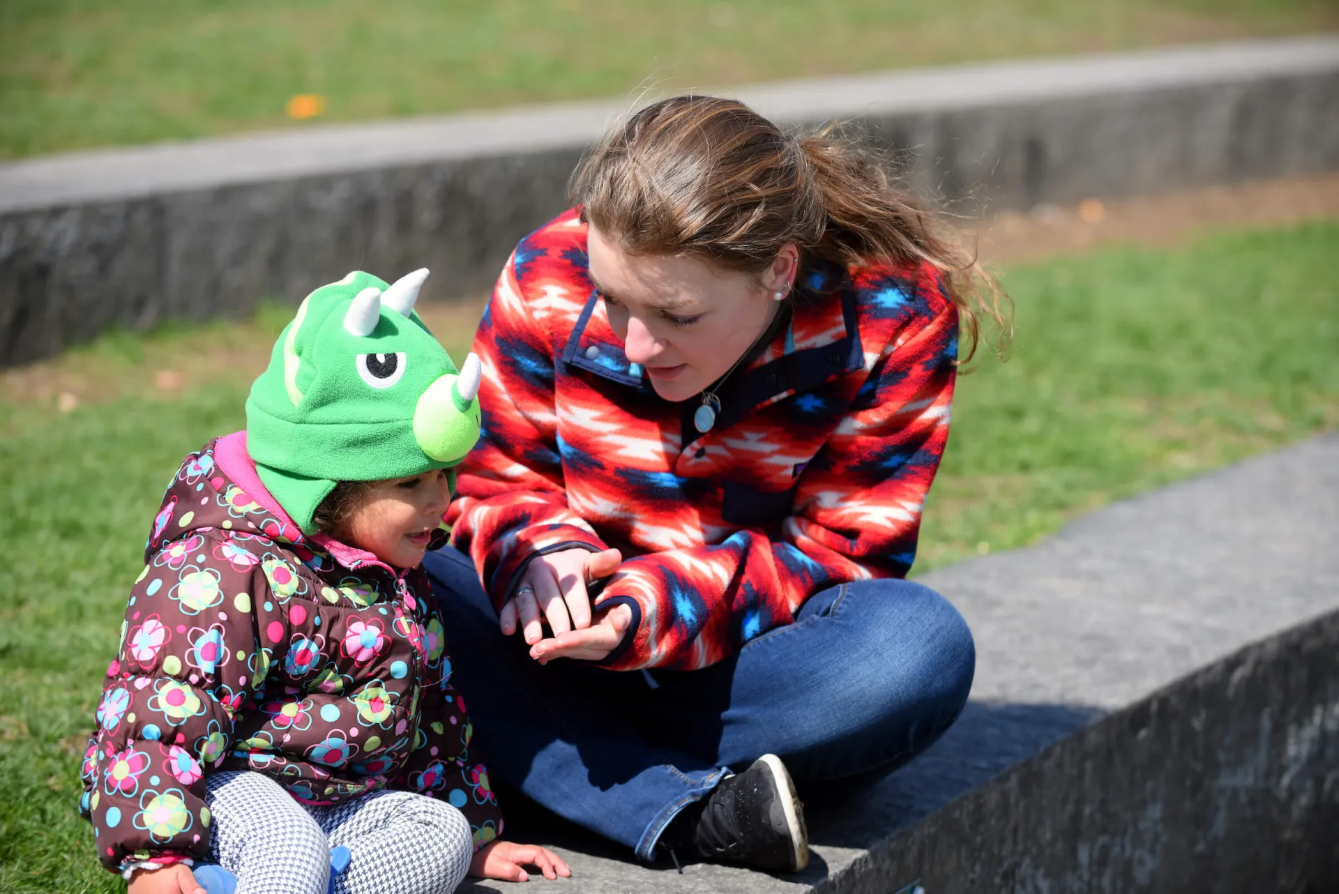 Student teacher engages with a young child during outdoor exploration time.