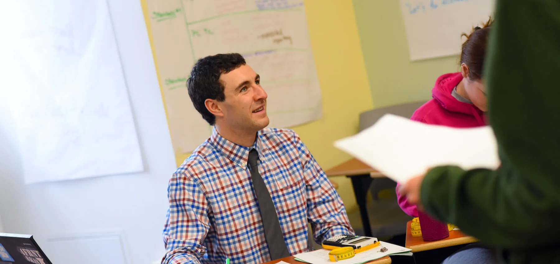 Educator engages with colleagues in a classroom meeting.
