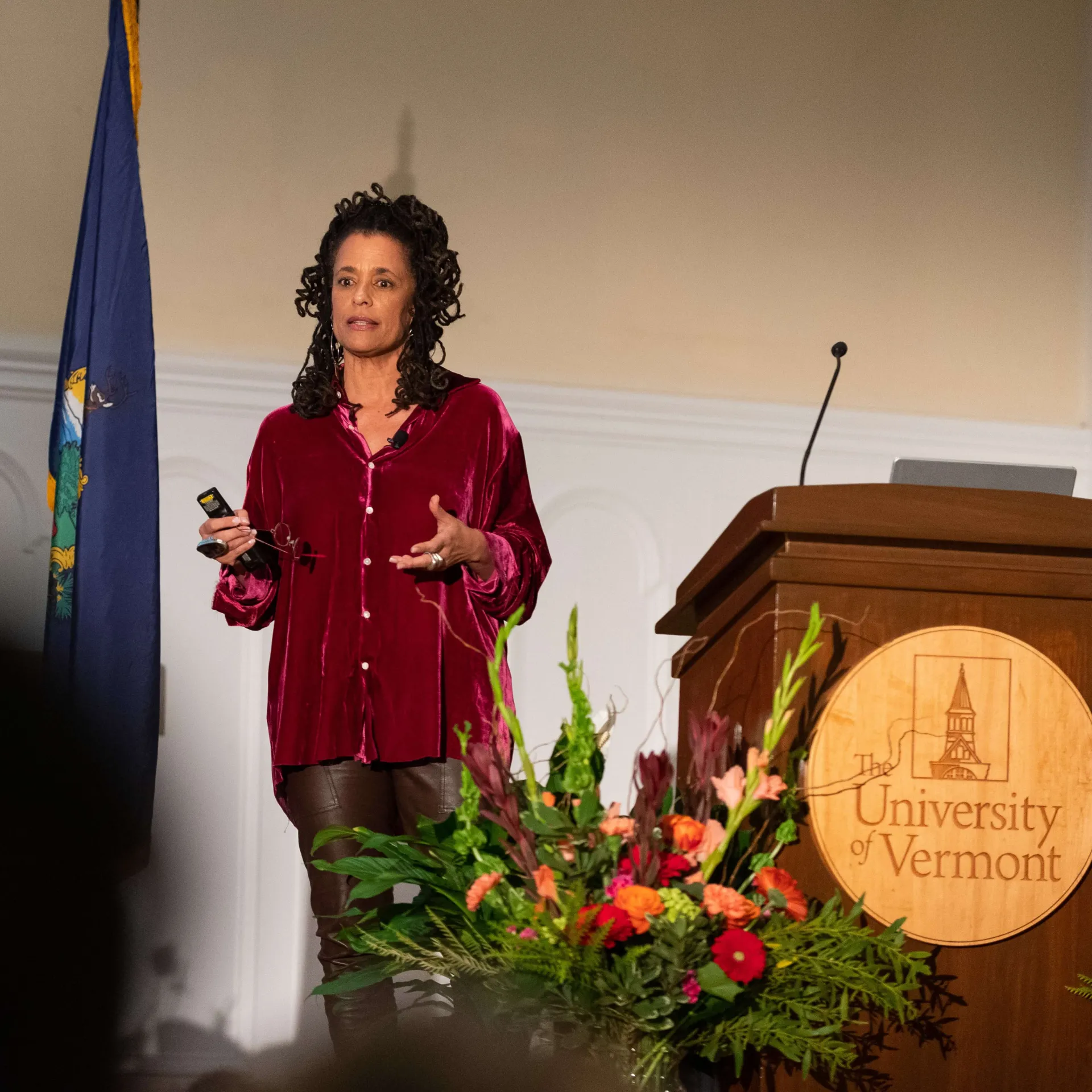 Caroline Finney standing on stage next to a podium at the Ira Allen Chapel.
