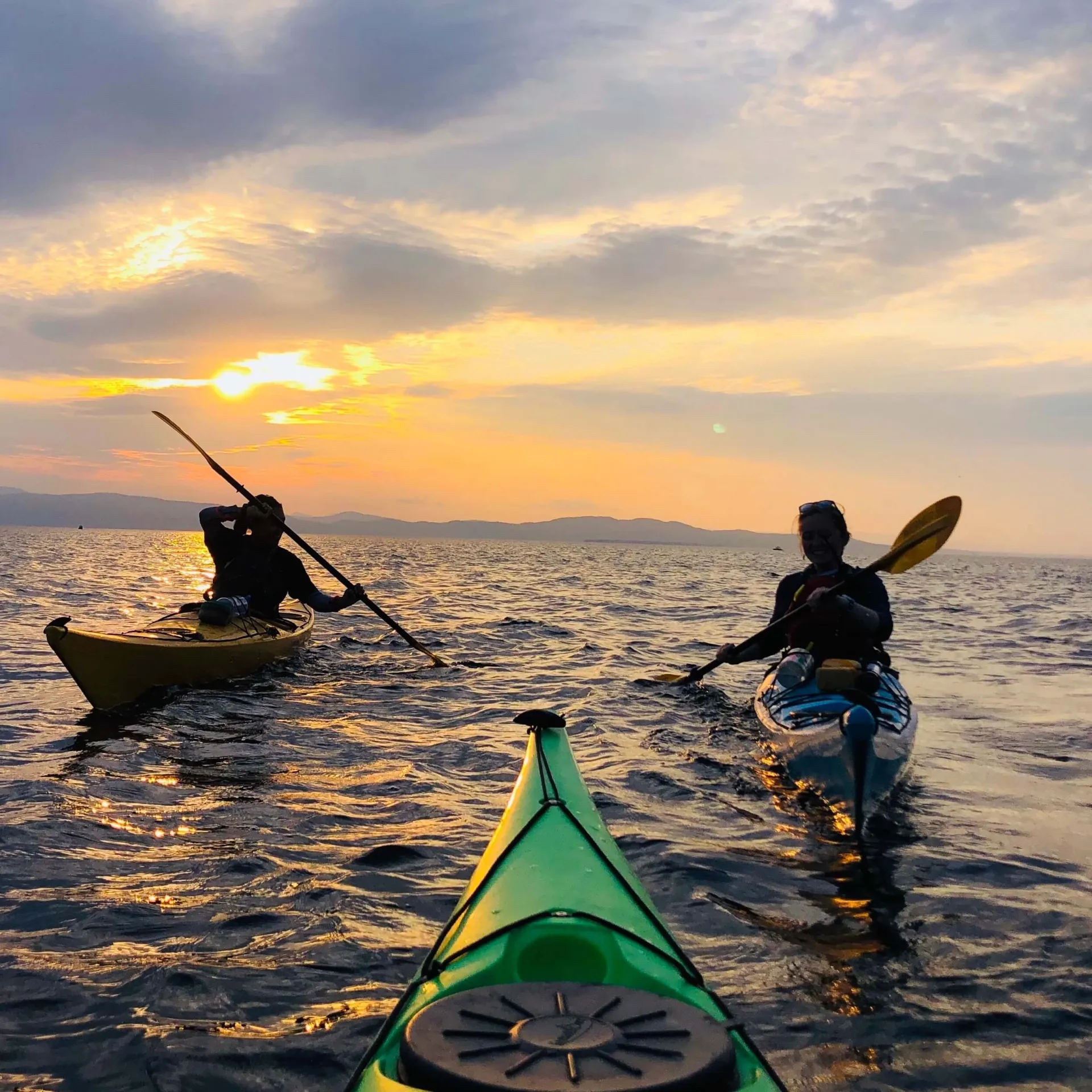 Students kayaking together into the sunset on Lake Champlain.