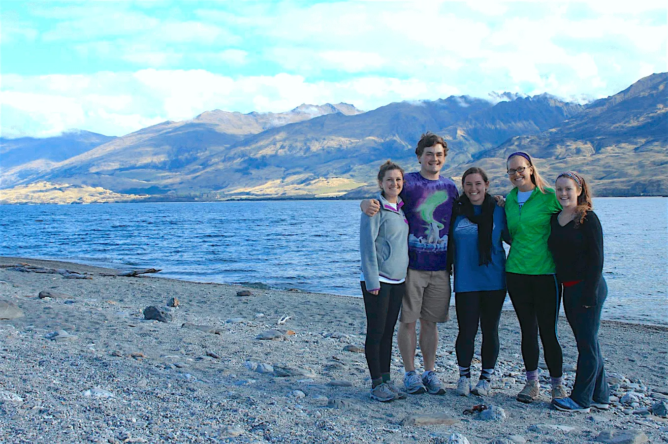 Students standing together in front of a lake and majestic mountains in New Zealand.