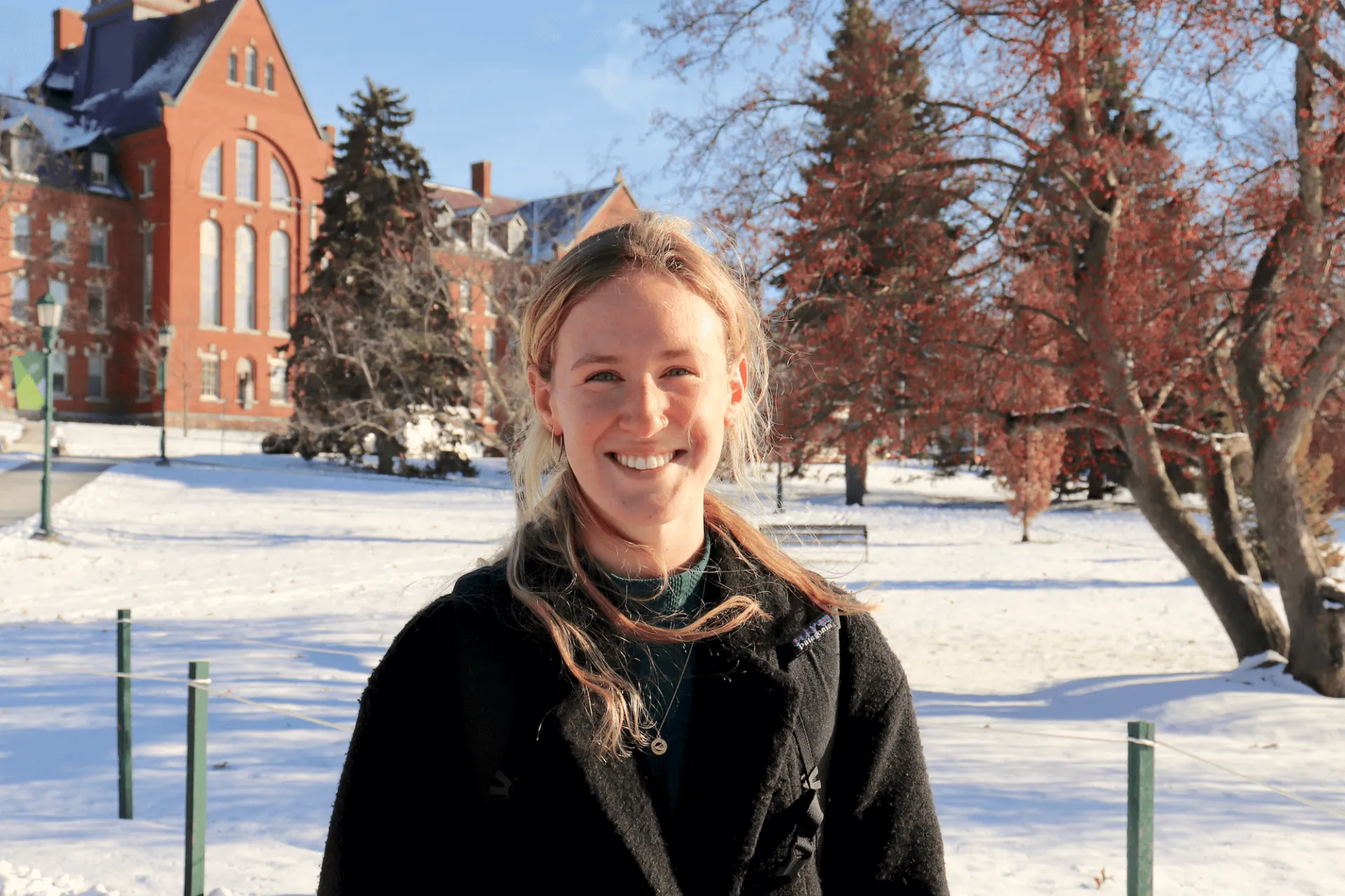 Phoebe Munch smiles as she stands on the University Green sidewalk on a sunny winter day