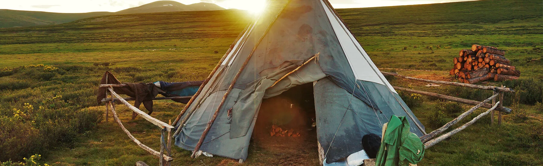 A teepee standing tall in a vast field under the clear blue sky.