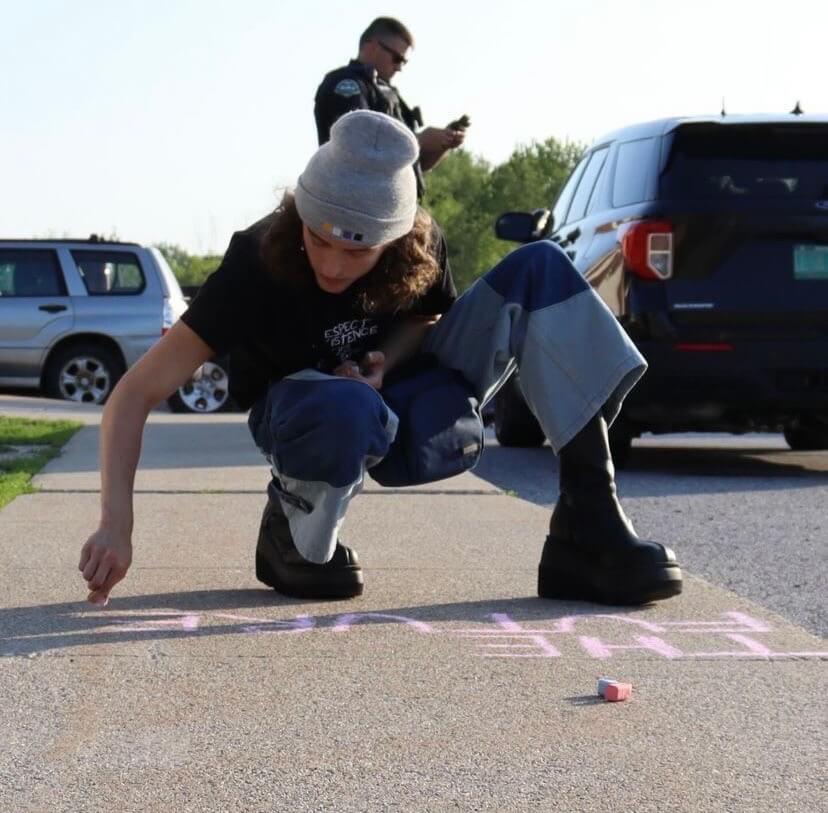 student writes message in chalk.