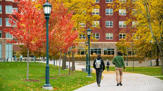 Students walk down a path outside among beautiful fall leaves