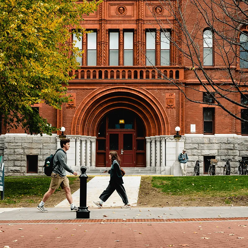 Two students walking in front of an academic building at the University of Vermont