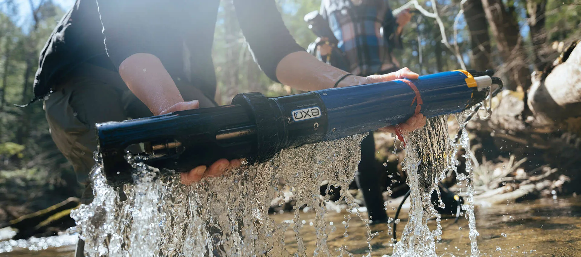 Researcher lifting a water sensor from a stream