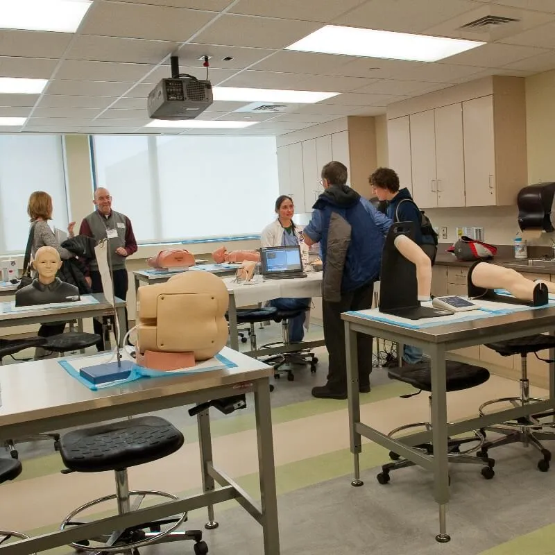 Faculty speak with students in the task trainer room