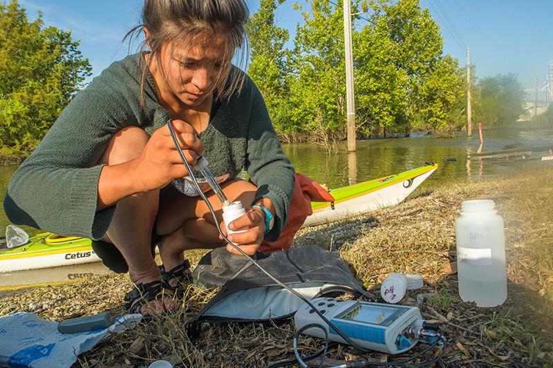 student researcher testing water in the field