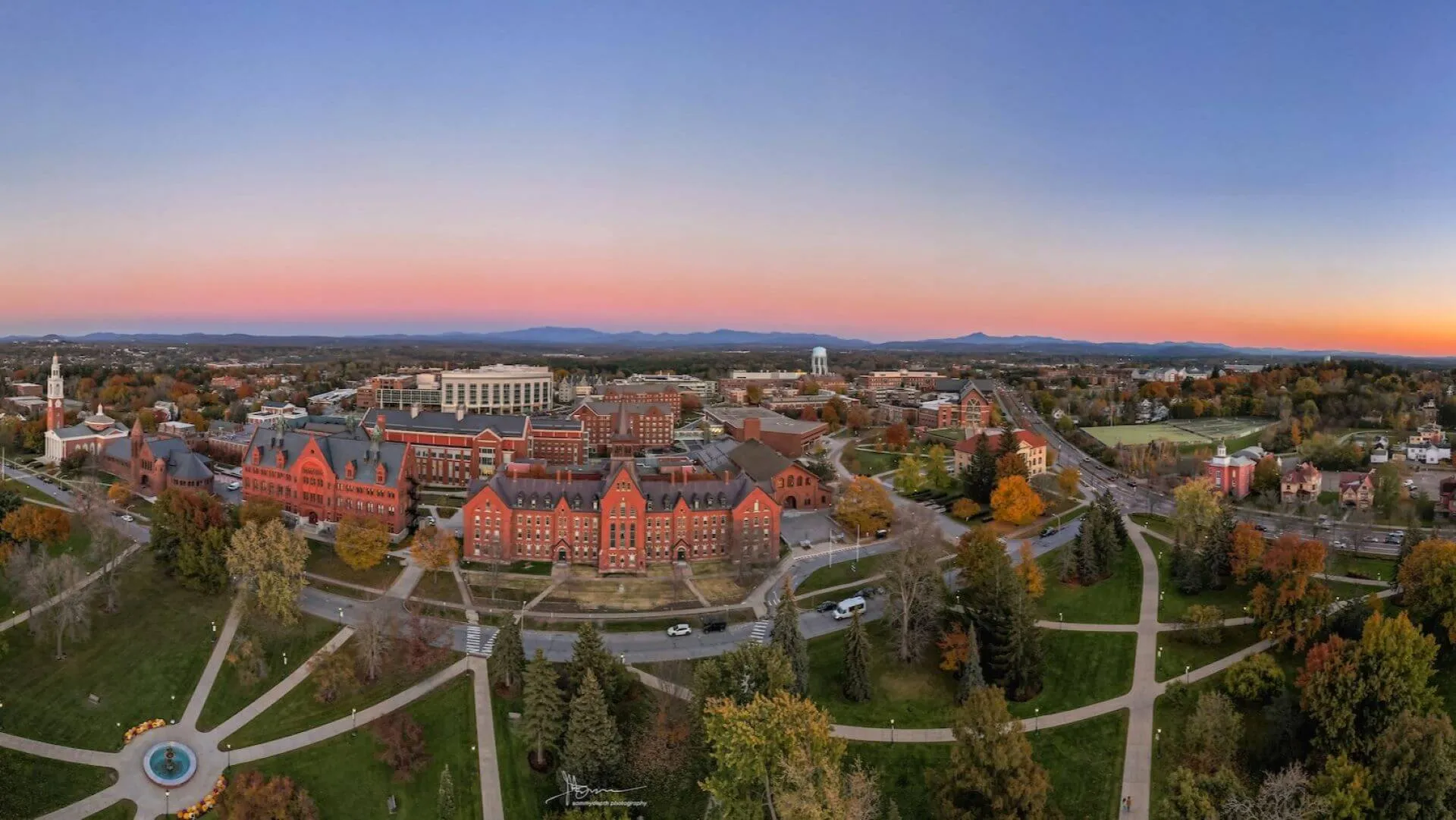 Drone shot of campus at sunrise with purple skies and mountains behind University Row