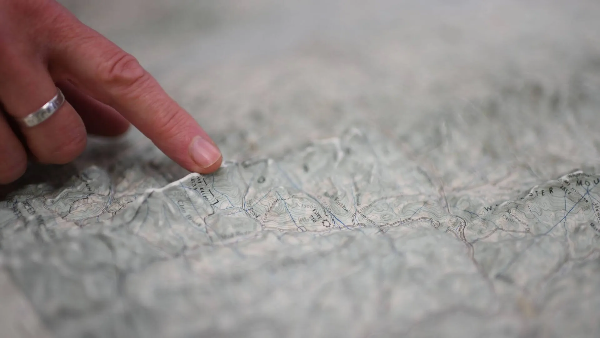 hand touching the raised ridge of a mountain on a topographic map