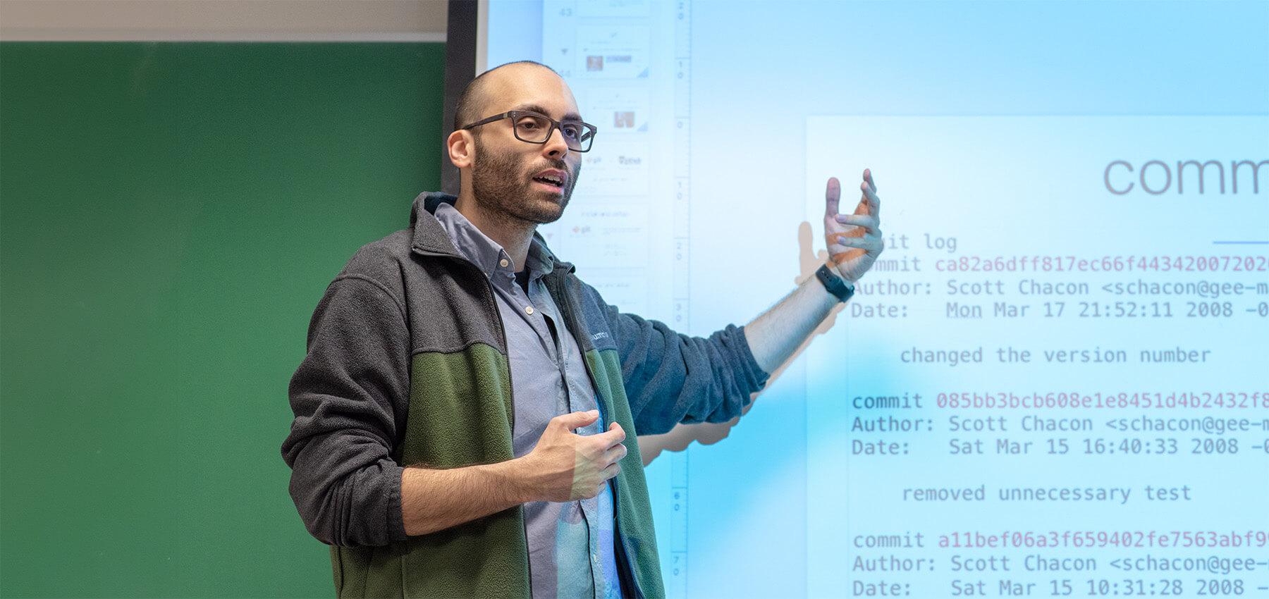 Professor giving lecture with a presentation in the background