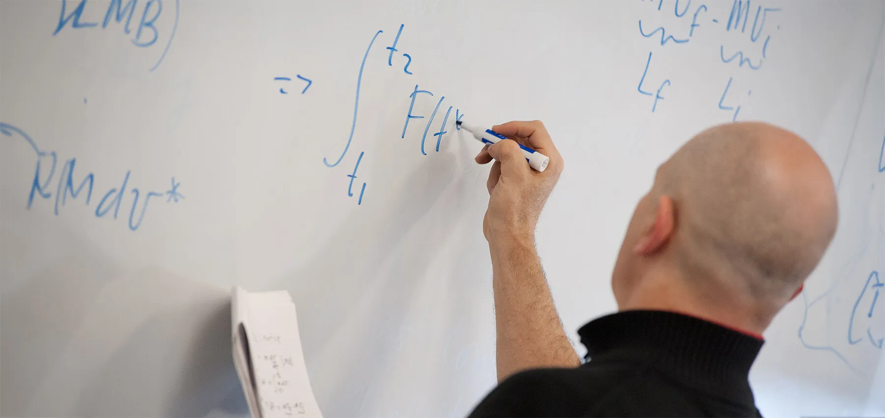 Professor writing an equation on a whiteboard