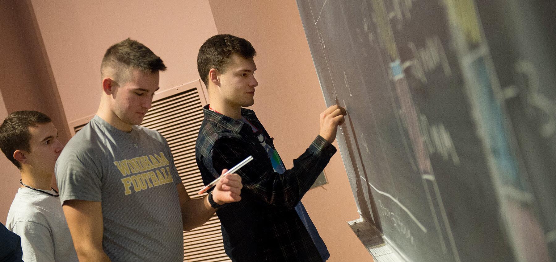 CEMS students solve a math problem at the blackboard