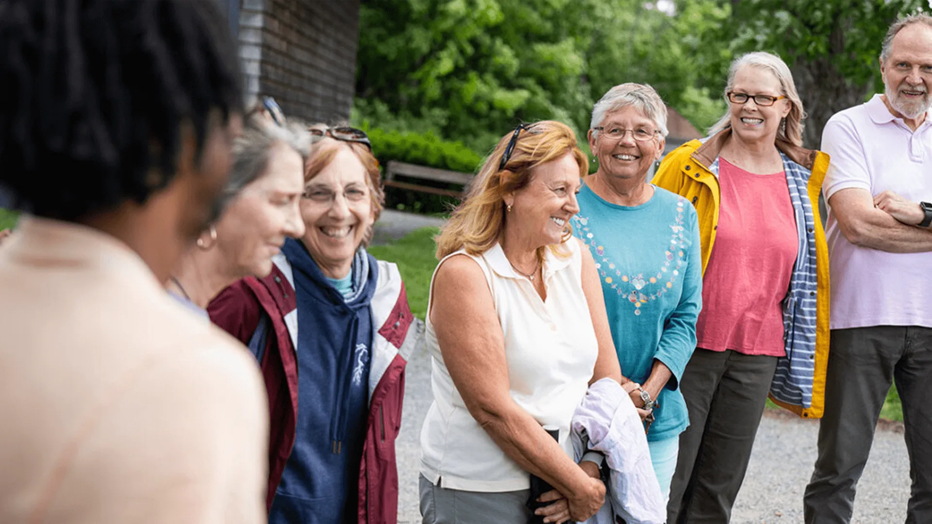 7 individuals standing in a group smiling while talking to each other