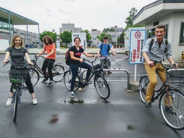 Several people on bicycles gather in front of a  building