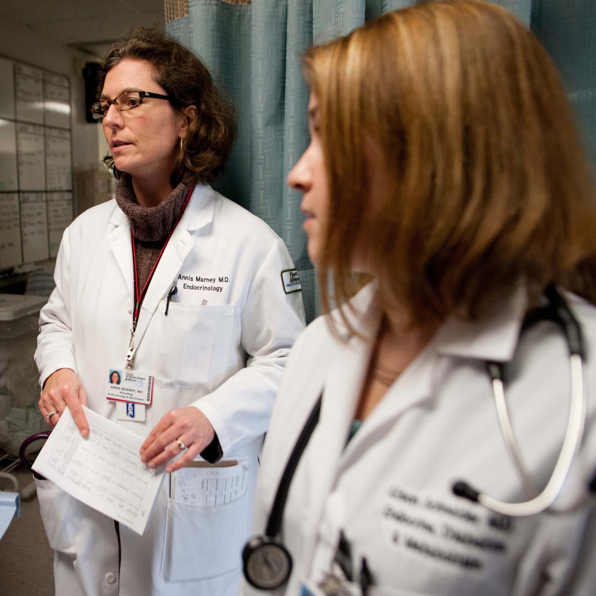 Two femme presenting doctors in a clinical setting.