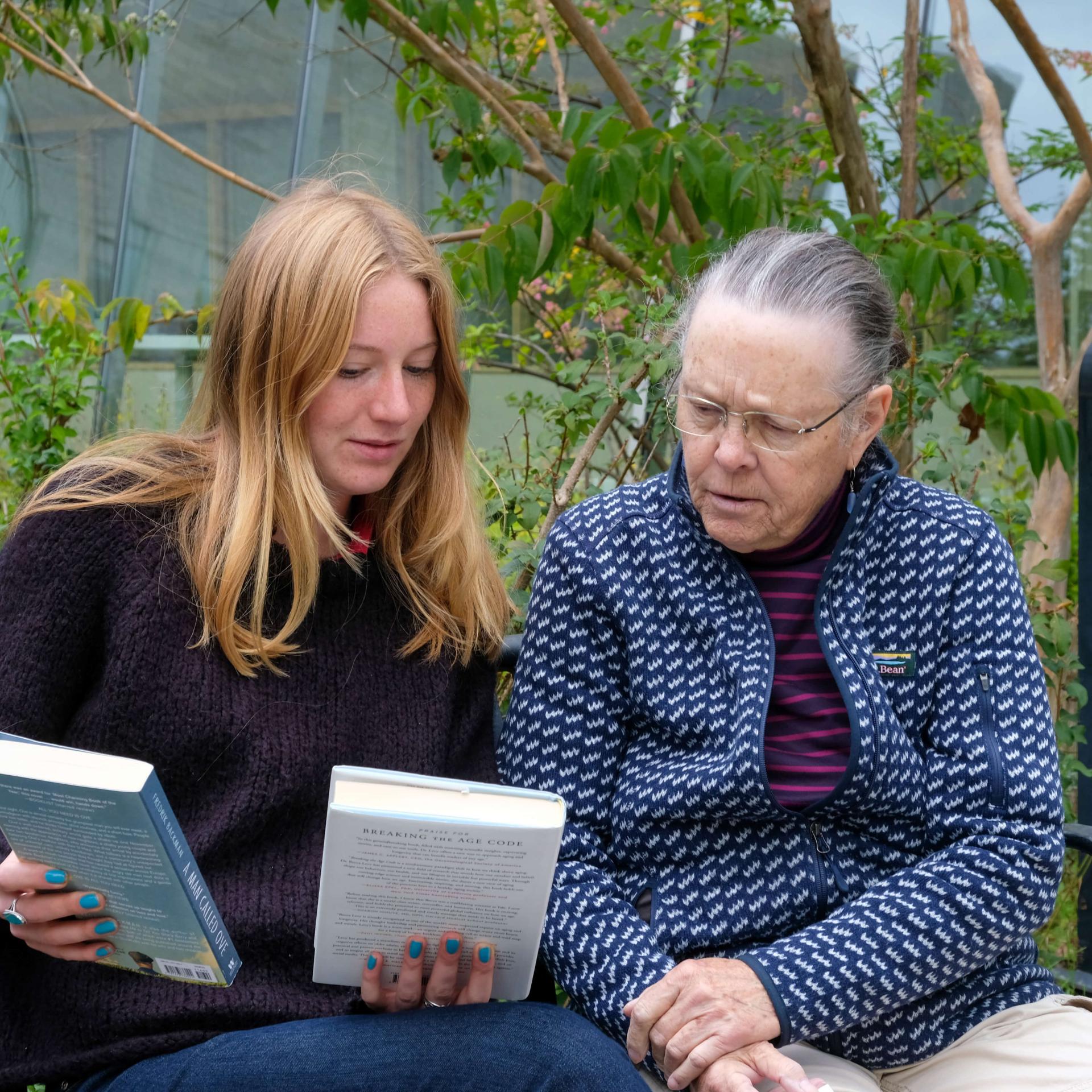 A student showing books to an elderly woman.