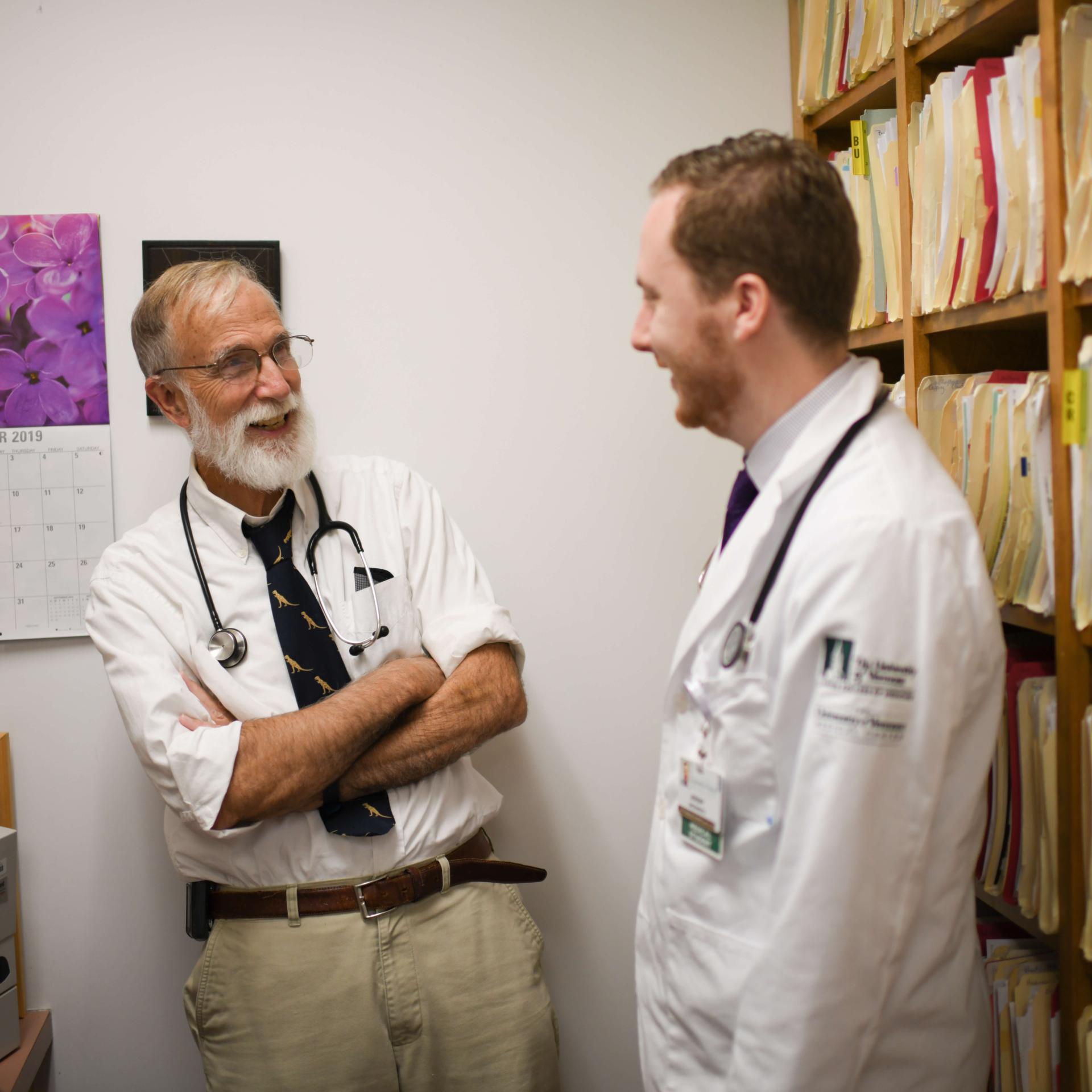 Two physicians smiling and conversing in a medical setting. 