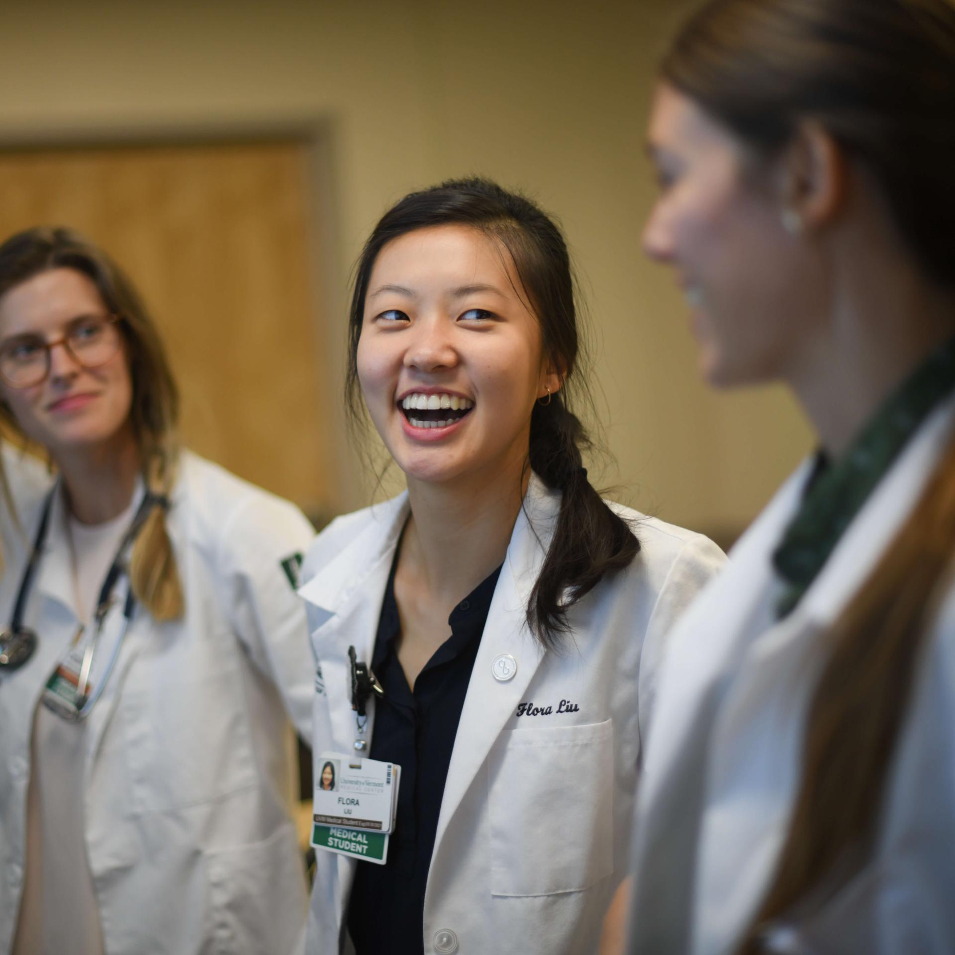 3 physicians smiling and conversing.