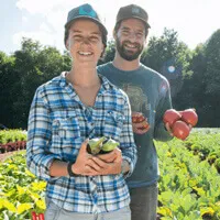 A man and a woman show off several apple specimens.