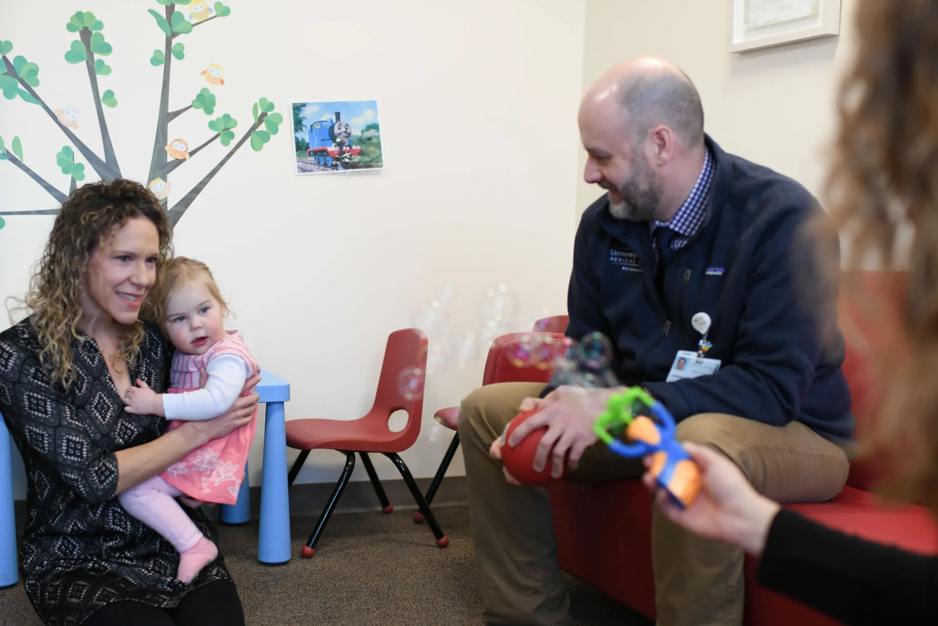 A pediatrician holds an infant, while sitting with two parents. 