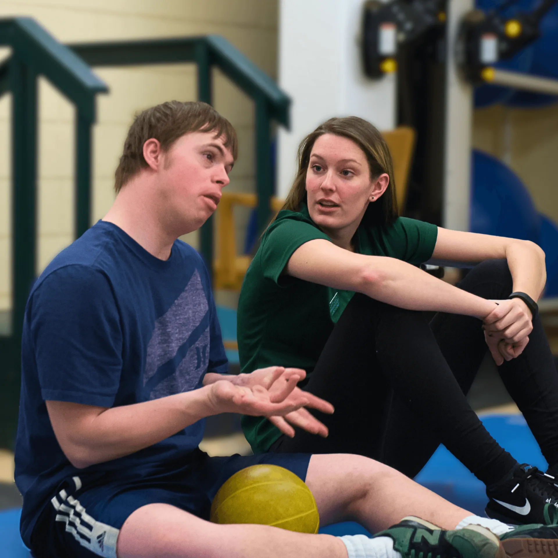 two students sitting on a mat in a gymnasium