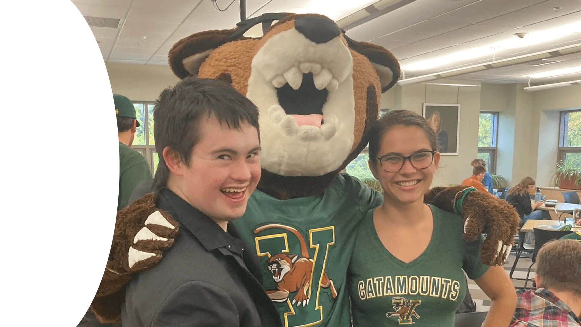Two college students, one with Down syndrome, pose for a photo with the Rallycat mascot