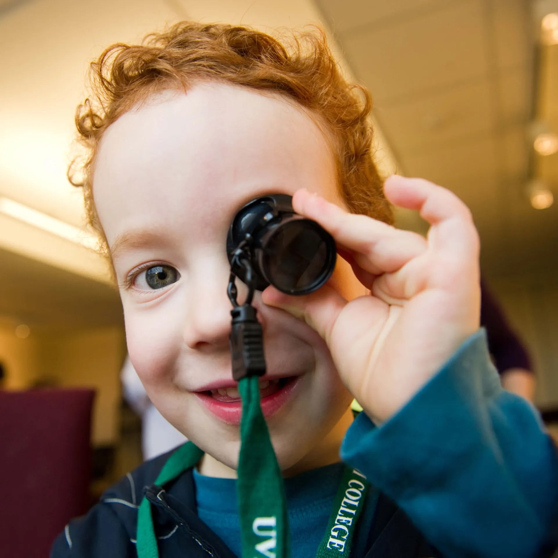 A child using a magnifying glass in front of the camera.