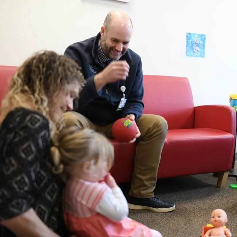 two adult playing with a toddler