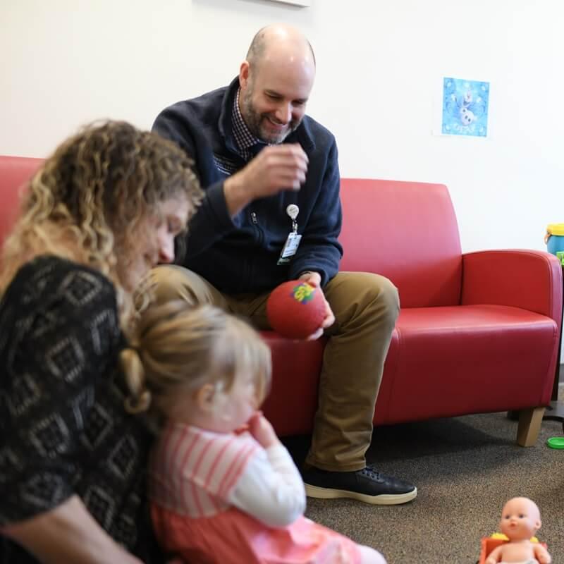 two adult playing with a toddler