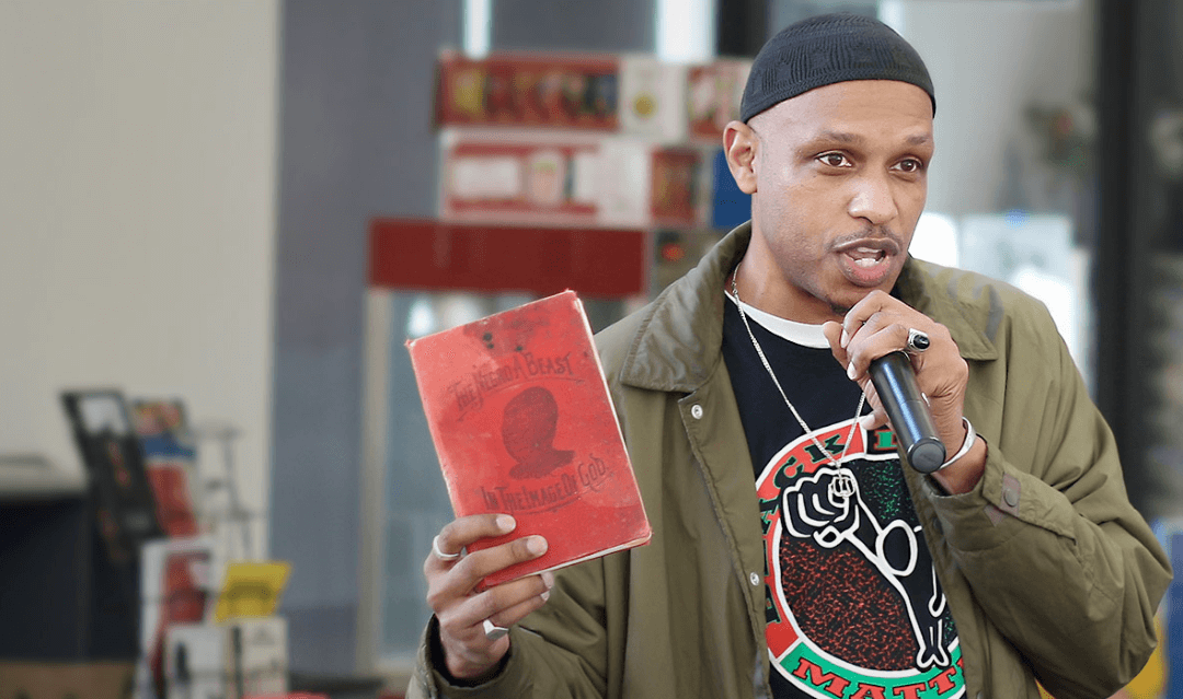 Khalid el-Hakim speaking while holding up an old book