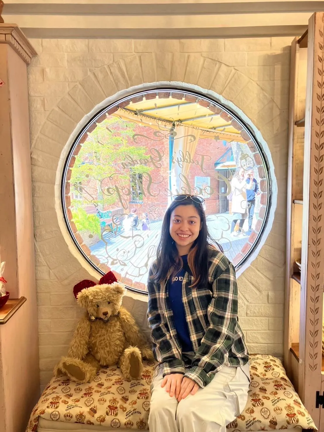 A woman sits on a bench, next to a toy teddy bear