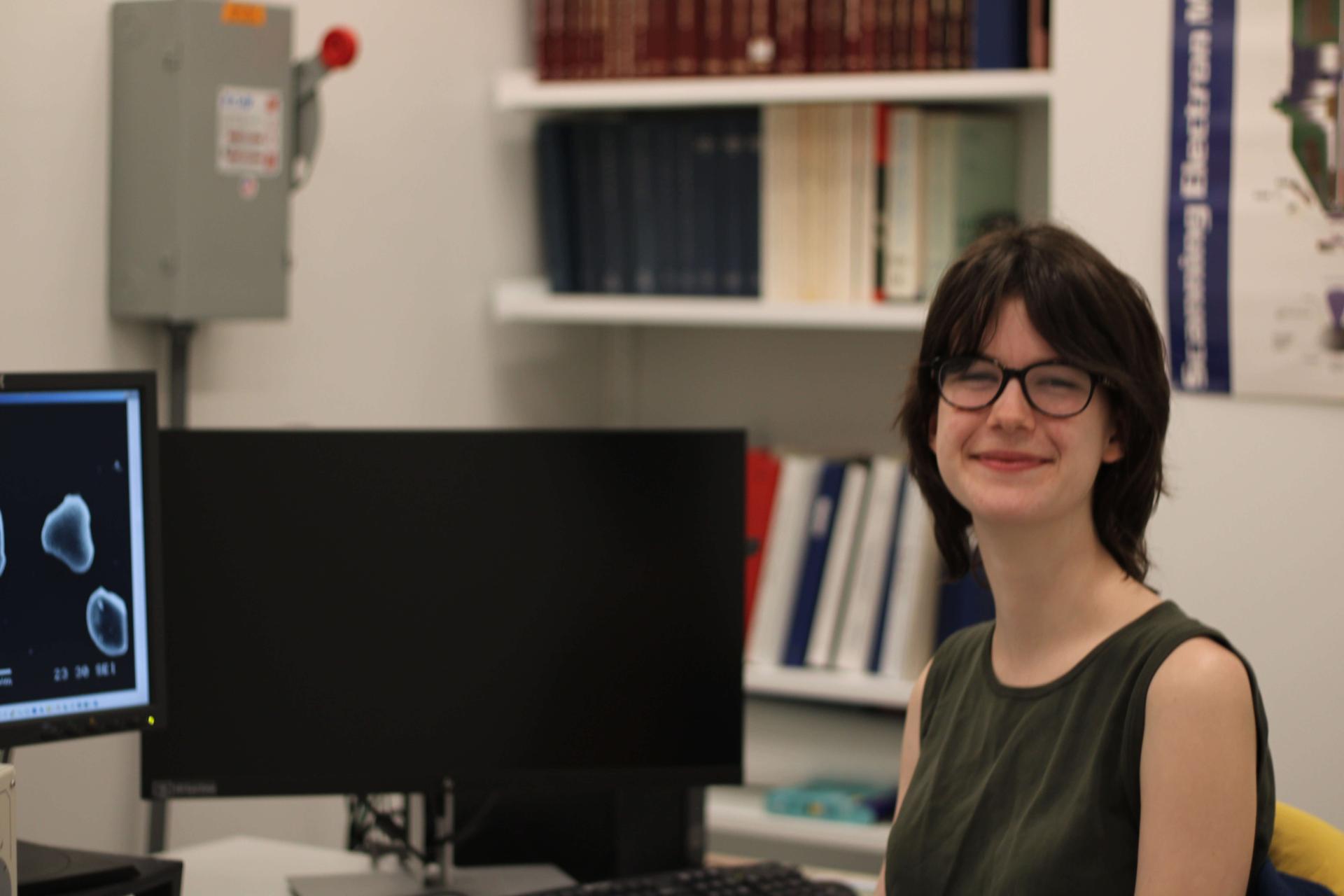 Student sitting by computer with research images on screen