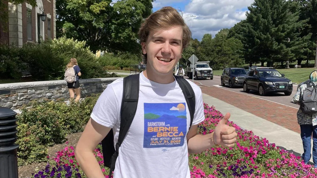 Chris standing outside of the Waterman Building on UVM's campus and giving a thumbs up