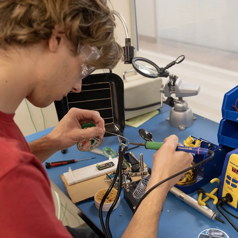 An electrical engineering student soldering on his capstone project