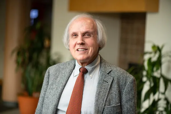 Dr. Stein smiling in gray suit, blue shirt, and burnt orange tie.