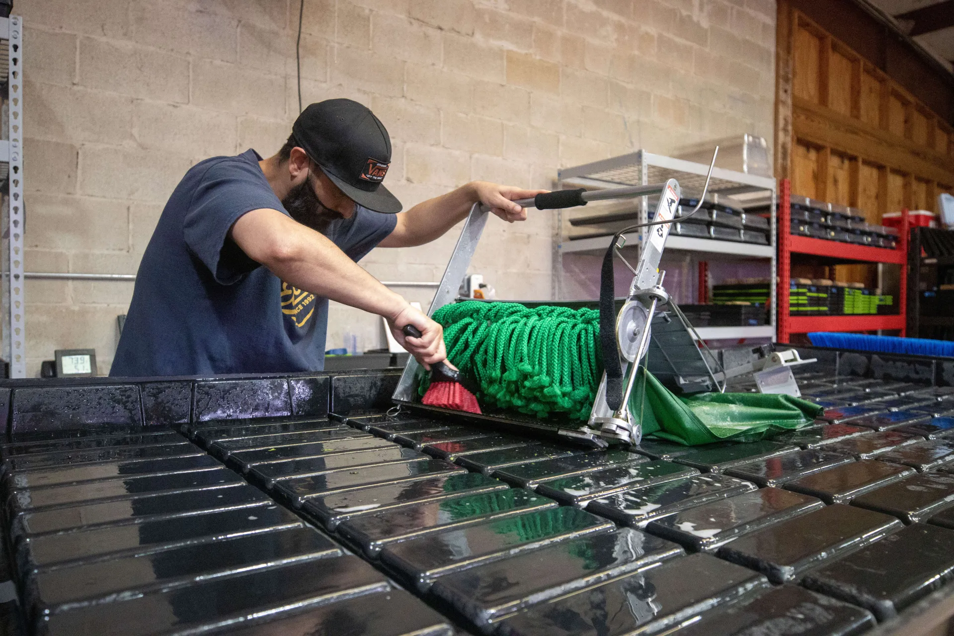 Worker scrubbing the Quick-Cut Greens Harvester with a brush