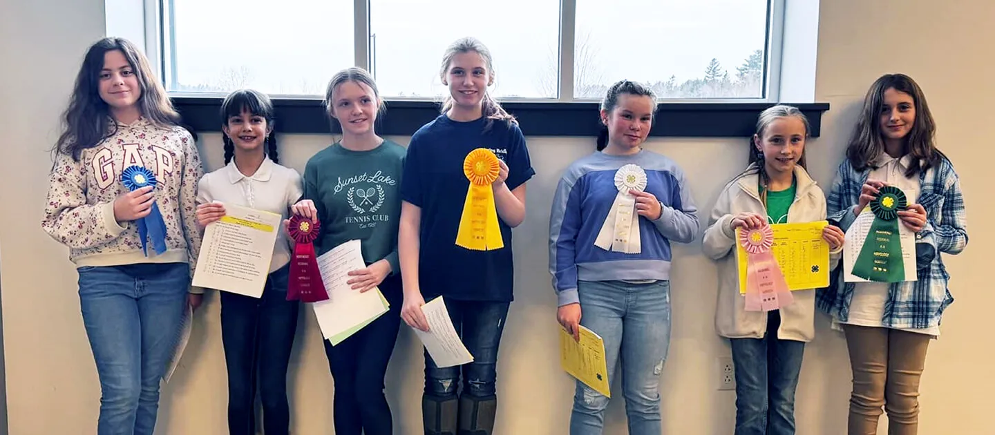 7 kids holding up prize ribbons