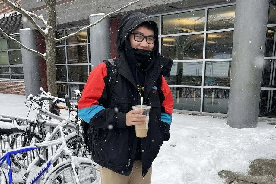 Ryan stands outside in the snow holding an iced coffee