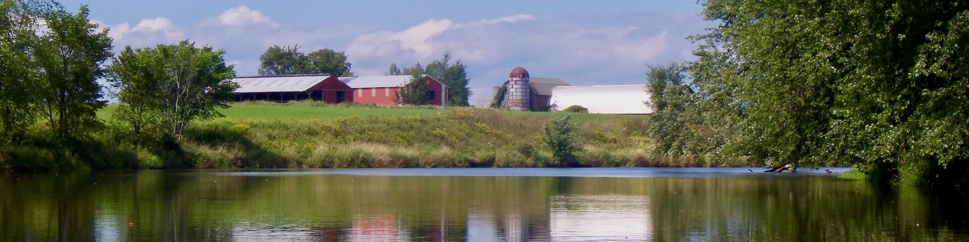 farm buildings near a calm river