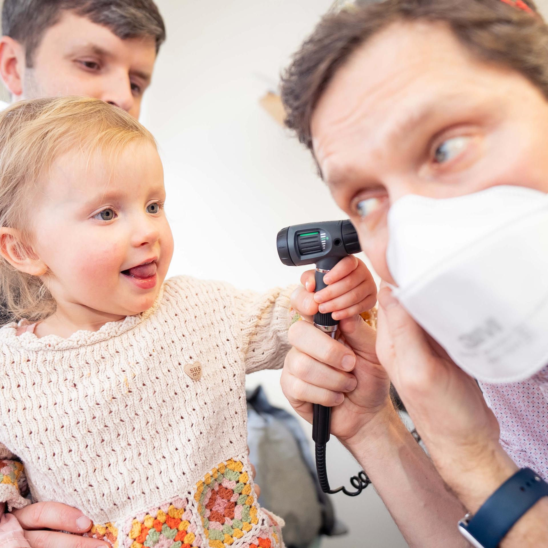 Child using ear thermometer on provider 