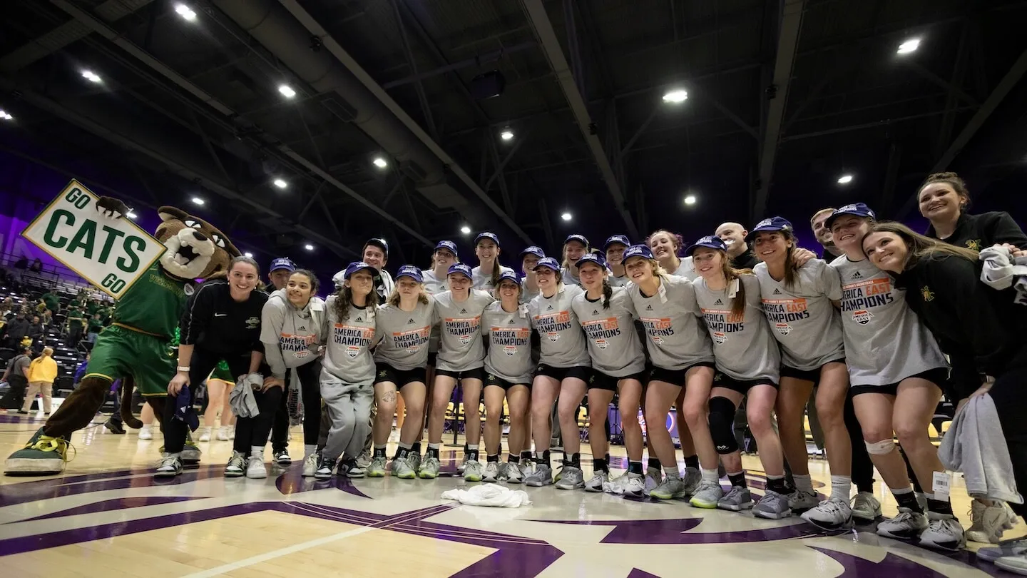 Rally Cat mascot and uvm women's basketball team lined up on court