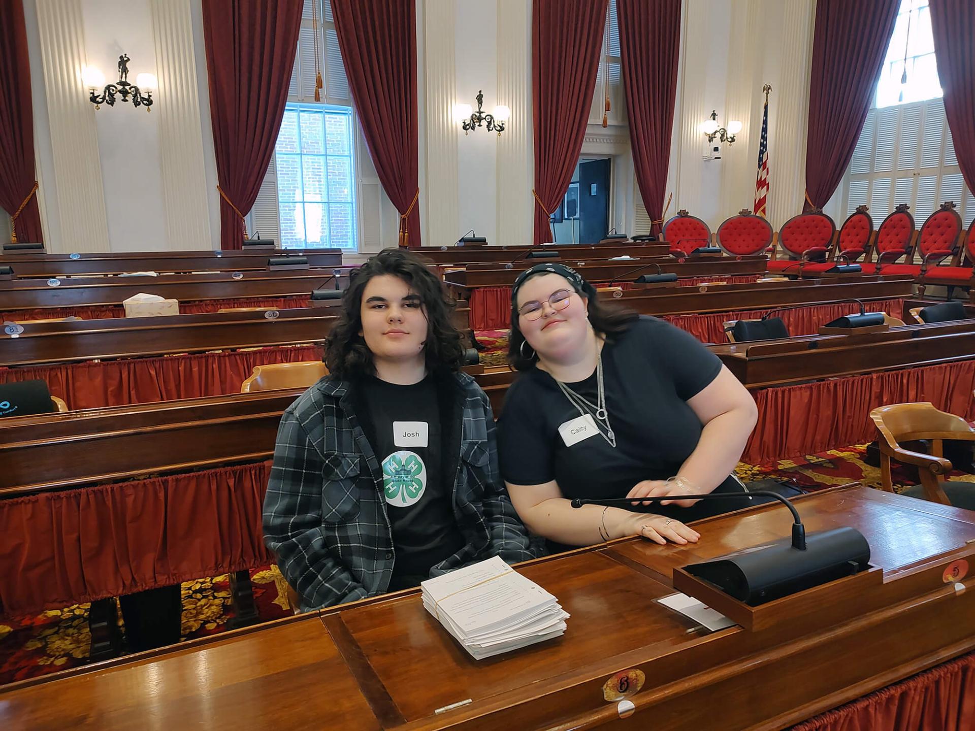 two youths sitting at a desk in a government conference room