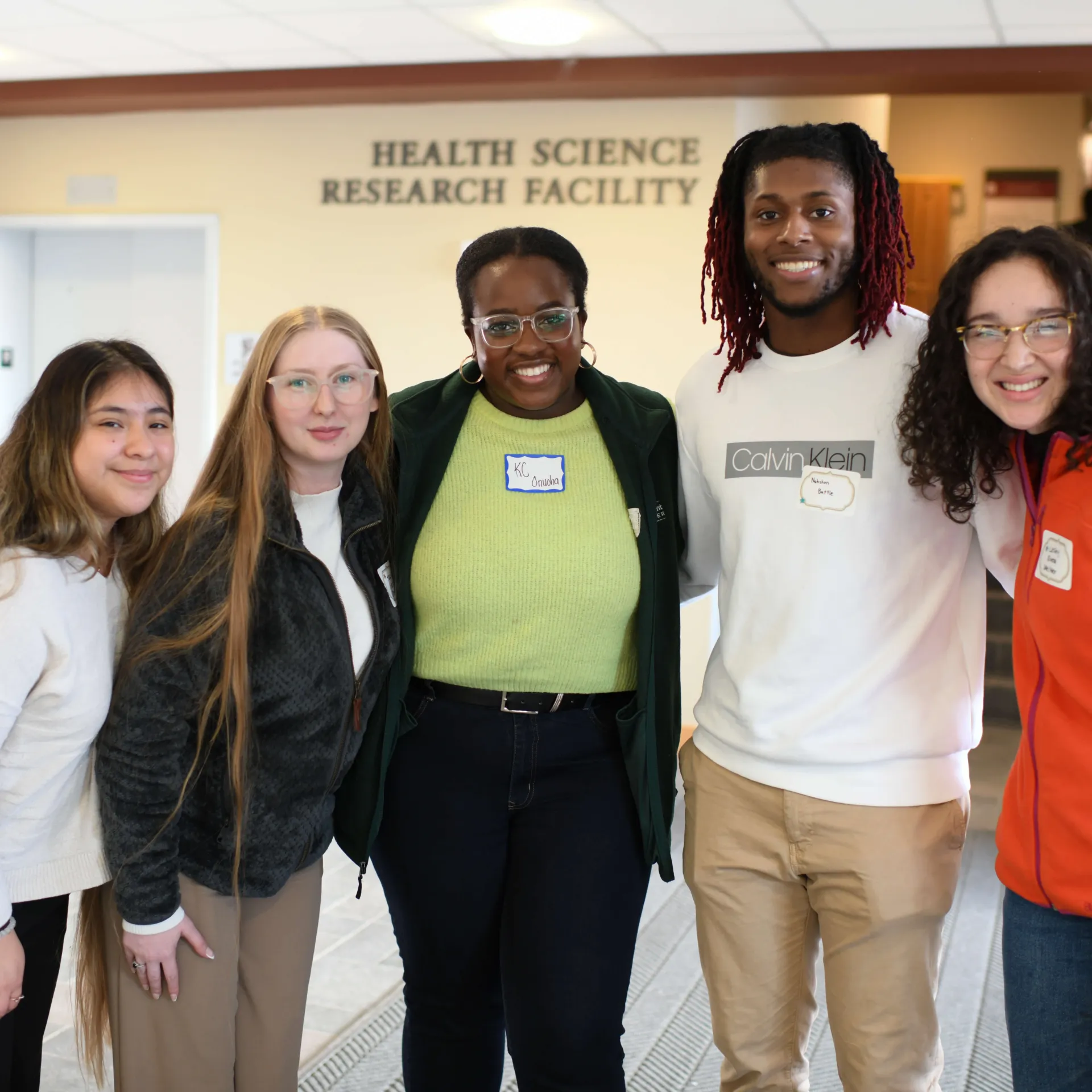 Five people smiling in front of the Health Science Research Facility building