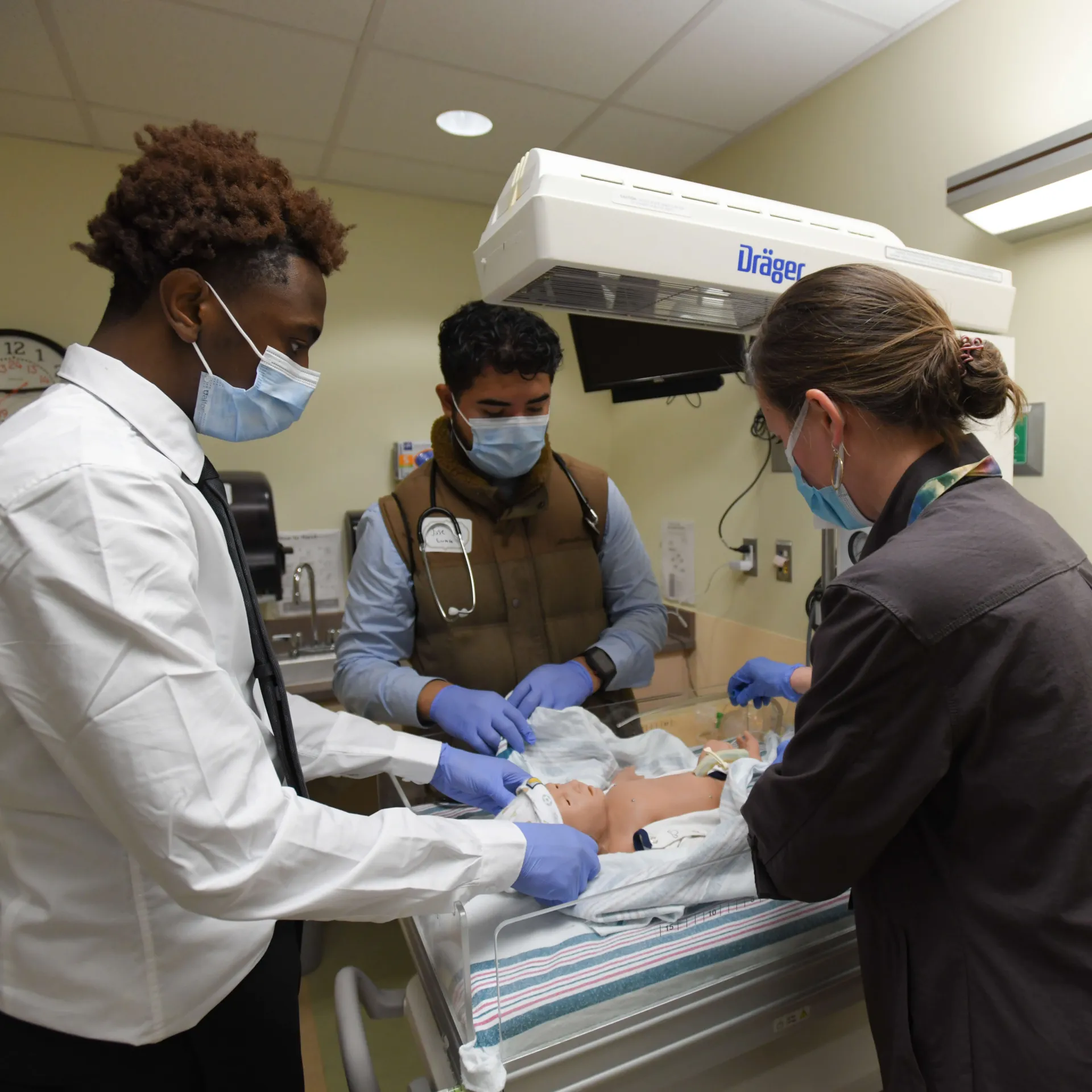 Three people practicing hands-on treatment on a medical dummy