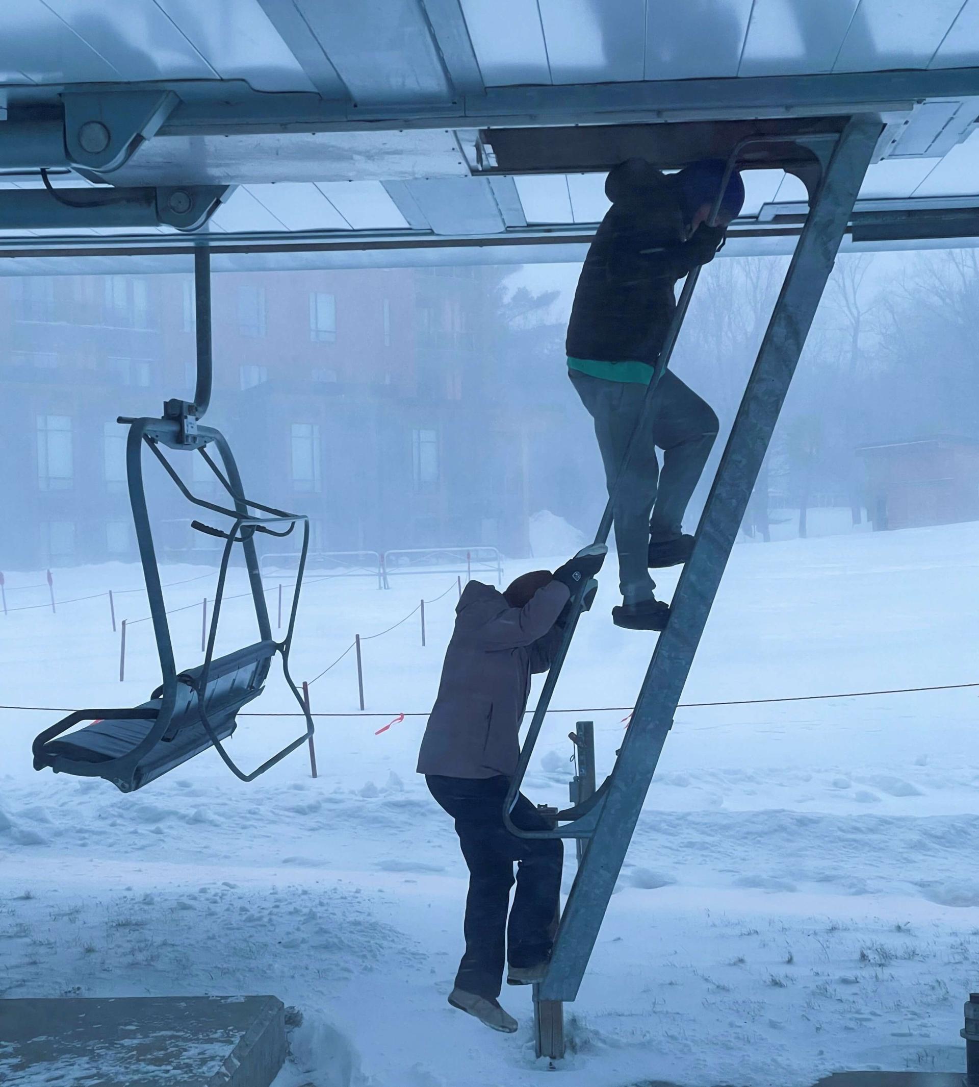 Students climb up a ladder into the operation center of a ski lift